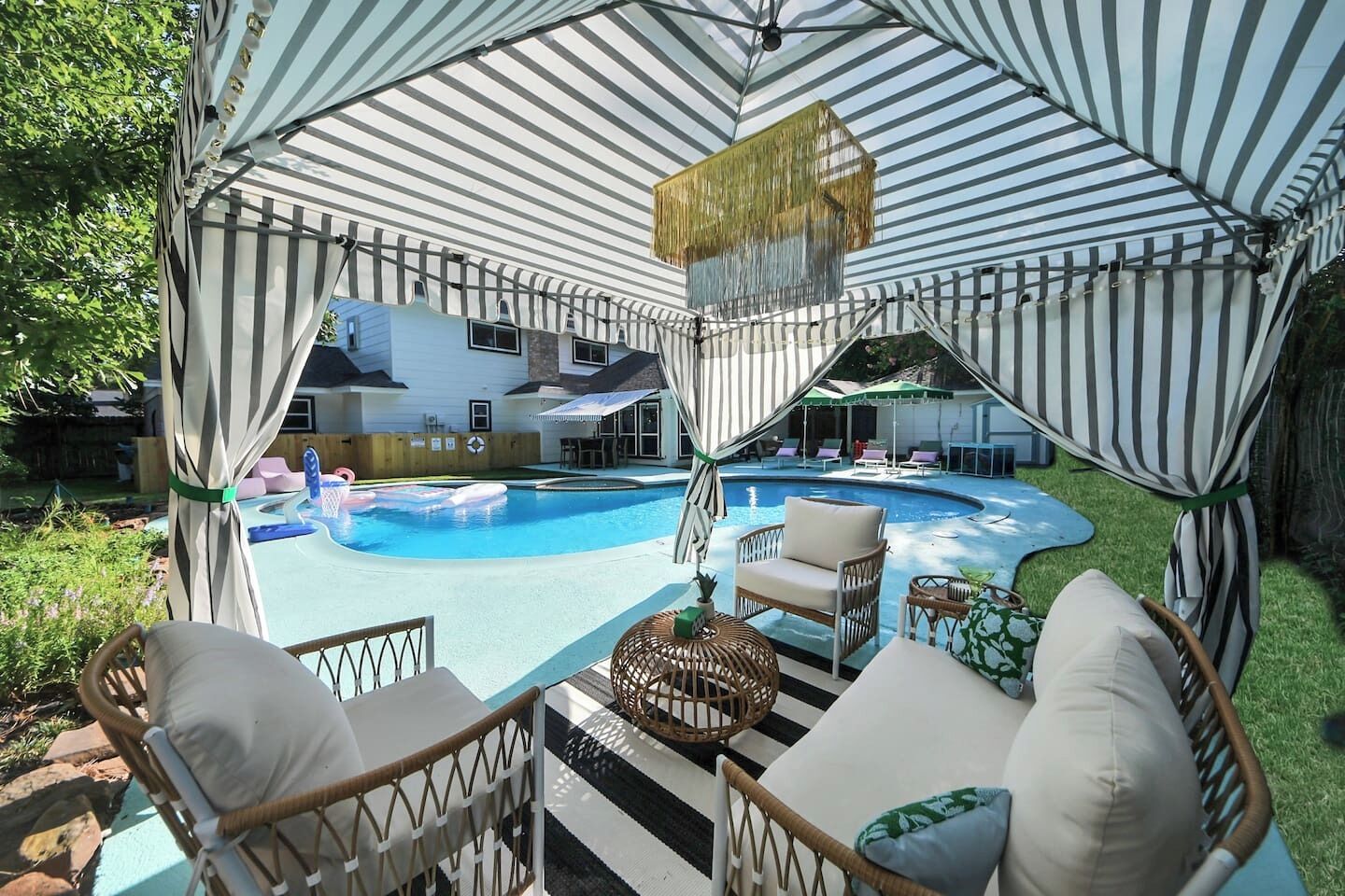Un espacio exterior techado con piscina, sillas de descanso y una mesa de comedor.