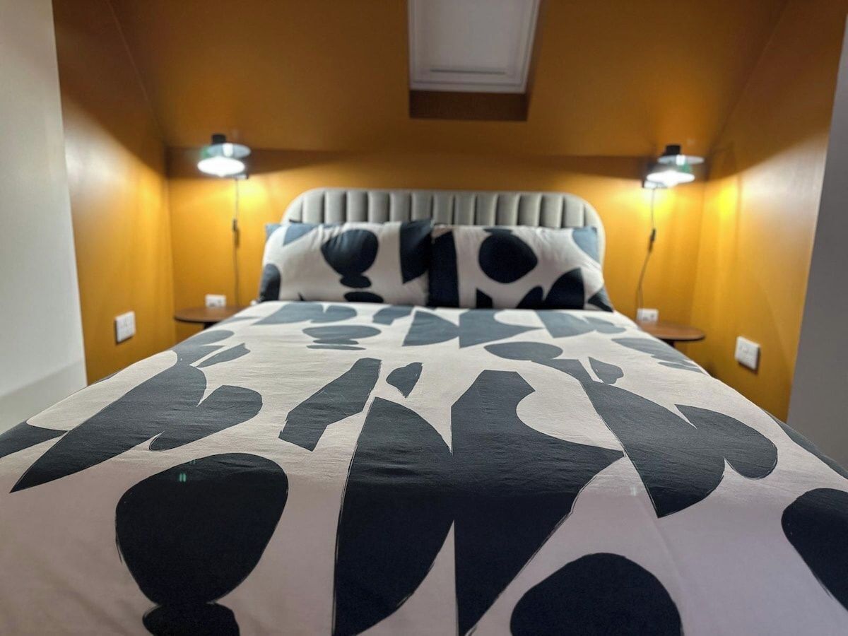 Un lit avec une couvre-lit à motifs, deux lampes de chevet et une tête de lit.