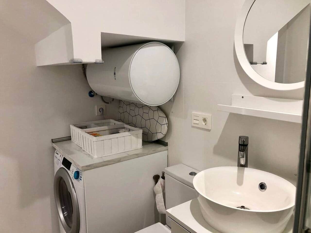 A compact bathroom with a washing machine, a toilet, and a sink.