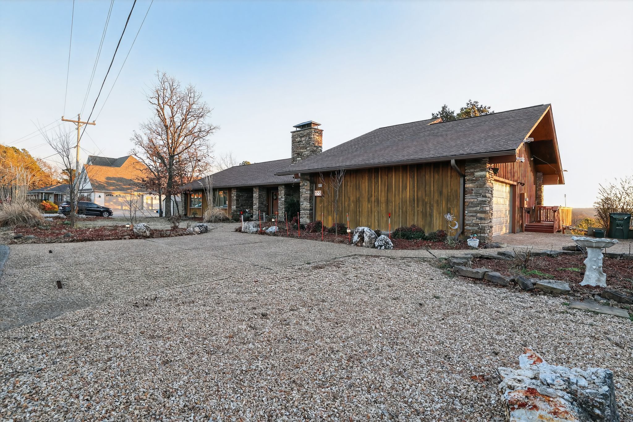 Un bâtiment de style rustique, doté d’une cheminée en pierre, d’une façade en bois et d’une allée gravillonnée.