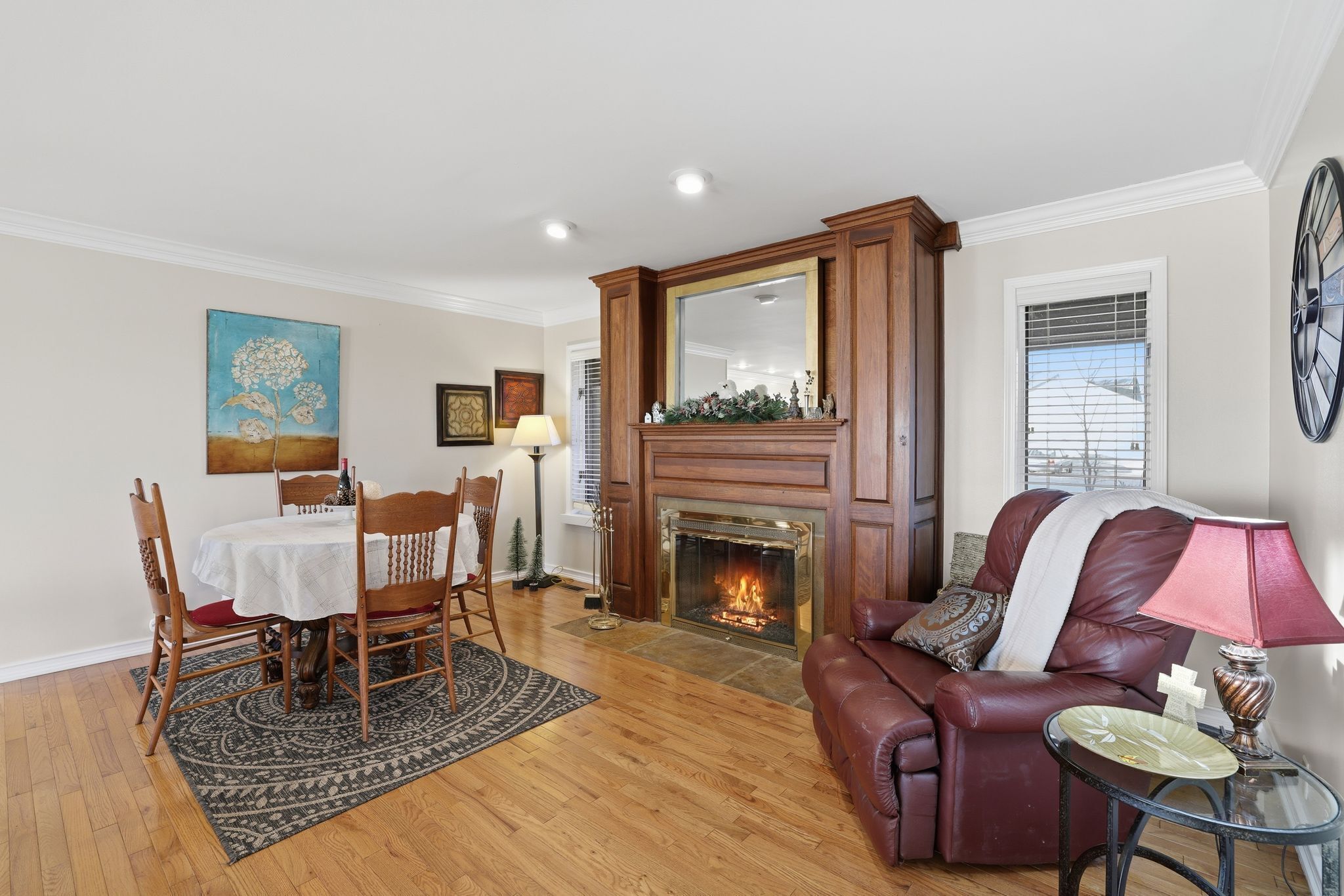 Un salon avec une cheminée, un coin repas avec une table et des chaises, et un canapé en cuir.