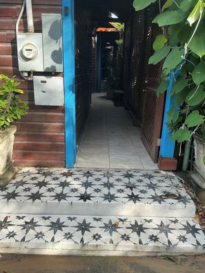 Un camí estret amb paviment de rajoles que condueix a l'entrada d'un edifici.