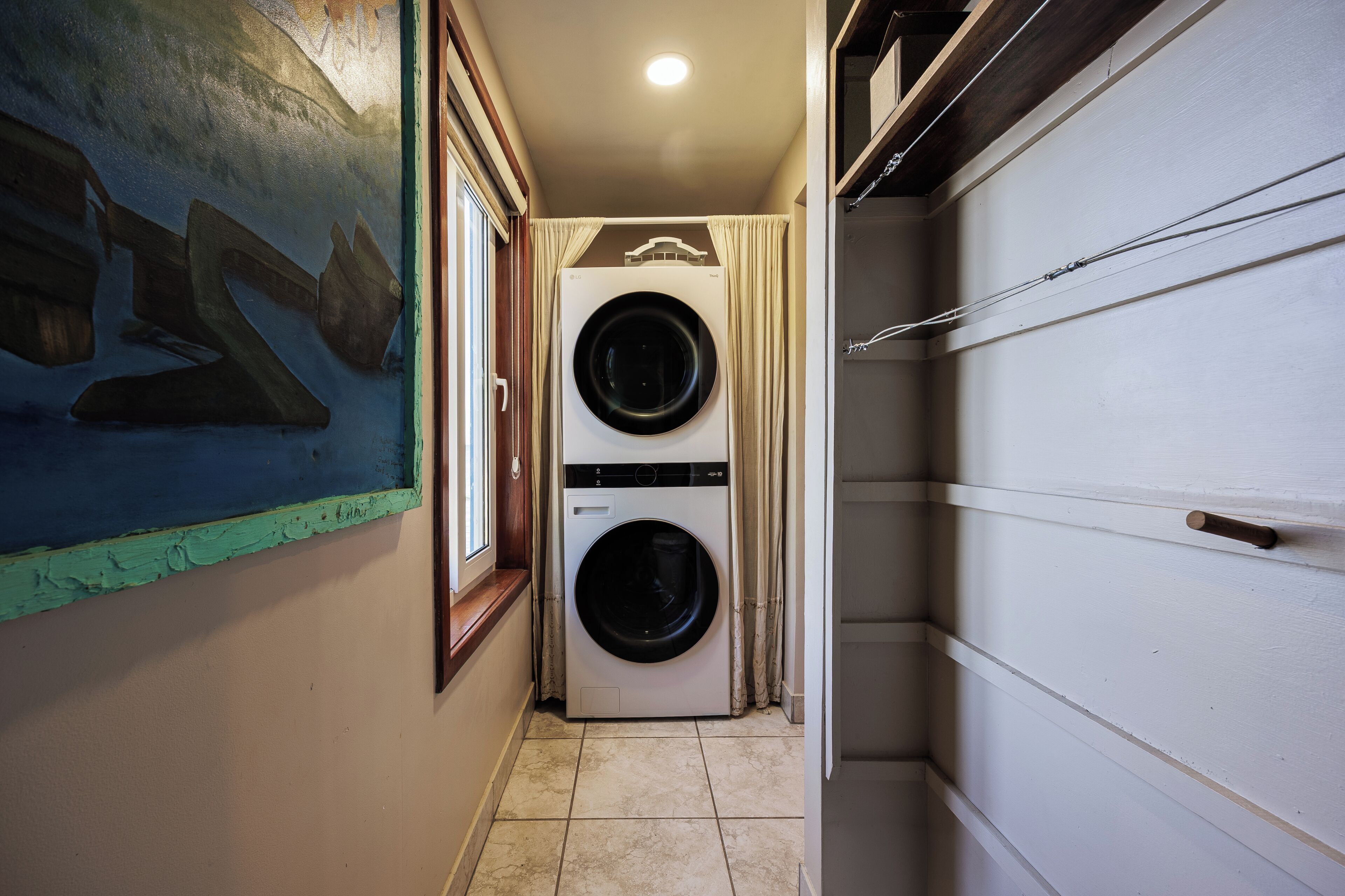 A laundry room with two stacked washing machines, a window, and a door.
