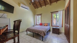Ein Schlafzimmer mit Bett, Schreibtisch, Stuhl, Fernseher, Klimaanlage und Fenster.