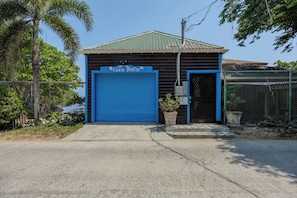 Un bâtiment avec une porte de garage bleue portant l’inscription « Casa Delfin », une clôture en métal et une allée en béton.