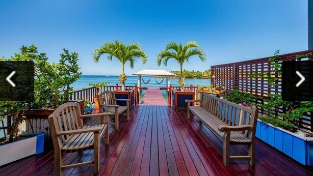 Eine Holzterrasse mit Bänken und Blick auf den Ozean.