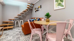 En modern inredning med en trappa, ett runt träbord och rosa stolar.
