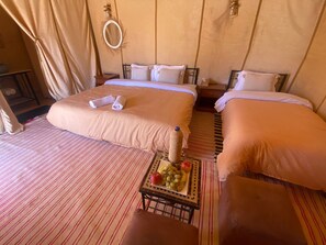 A hotel room with two beds, a small table with fruit, and a mirror on the wall. - Merzouga Luxury tent (Merzouga)