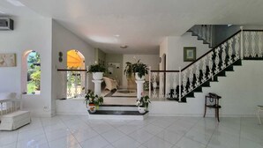 Un vaste espace de vie comprenant un escalier, des plantes en pot et une vue sur l’extérieur.