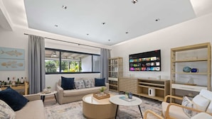 Uma sala de estar moderna com sofá, mesa de centro, televisão e prateleiras.
