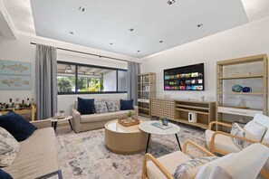 En moderne stue med sofa, sofabord, fjernsyn og reoler.