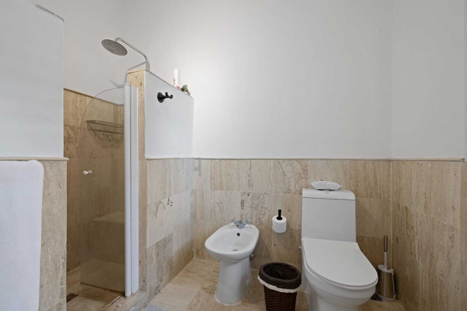 Une salle de bain équipée d’une douche, de toilettes, d’un bidet et d’une poubelle.