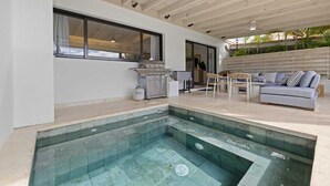 Cozinha externa moderna com piscina, área de estar e vista para o exterior.