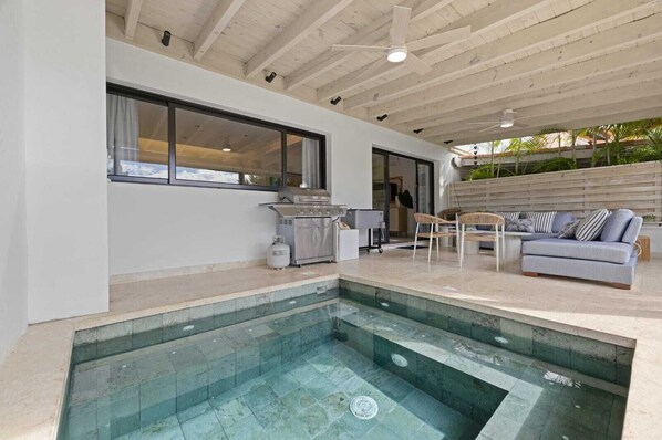 A modern outdoor kitchen with a pool, seating area, and a view of the outdoors.
