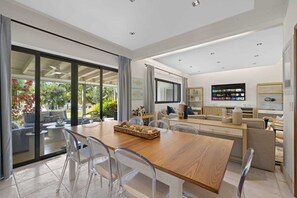 A modern kitchen with a dining area, a TV, and a view of the outdoors.