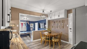 Una cocina moderna con suelo de madera, un comedor con mesa y sillas de madera, y una pared con raquetas de tenis.