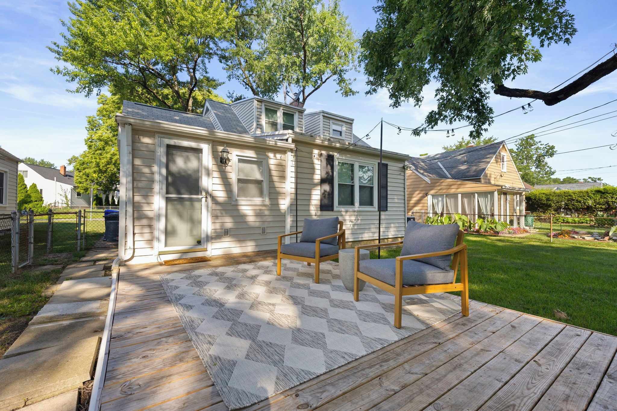 A house with a deck, two chairs, and a small garden.