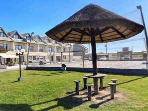 A residential area with a large umbrella structure, a lawn, and a row of houses.
