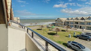 A seaside hotel with a balcony overlooking the ocean, a playground, and multiple cars parked in the driveway. - Houses in a Beachfront Condominium With a Swimming Pool in Itajuba - Mcss (Barra Velha)