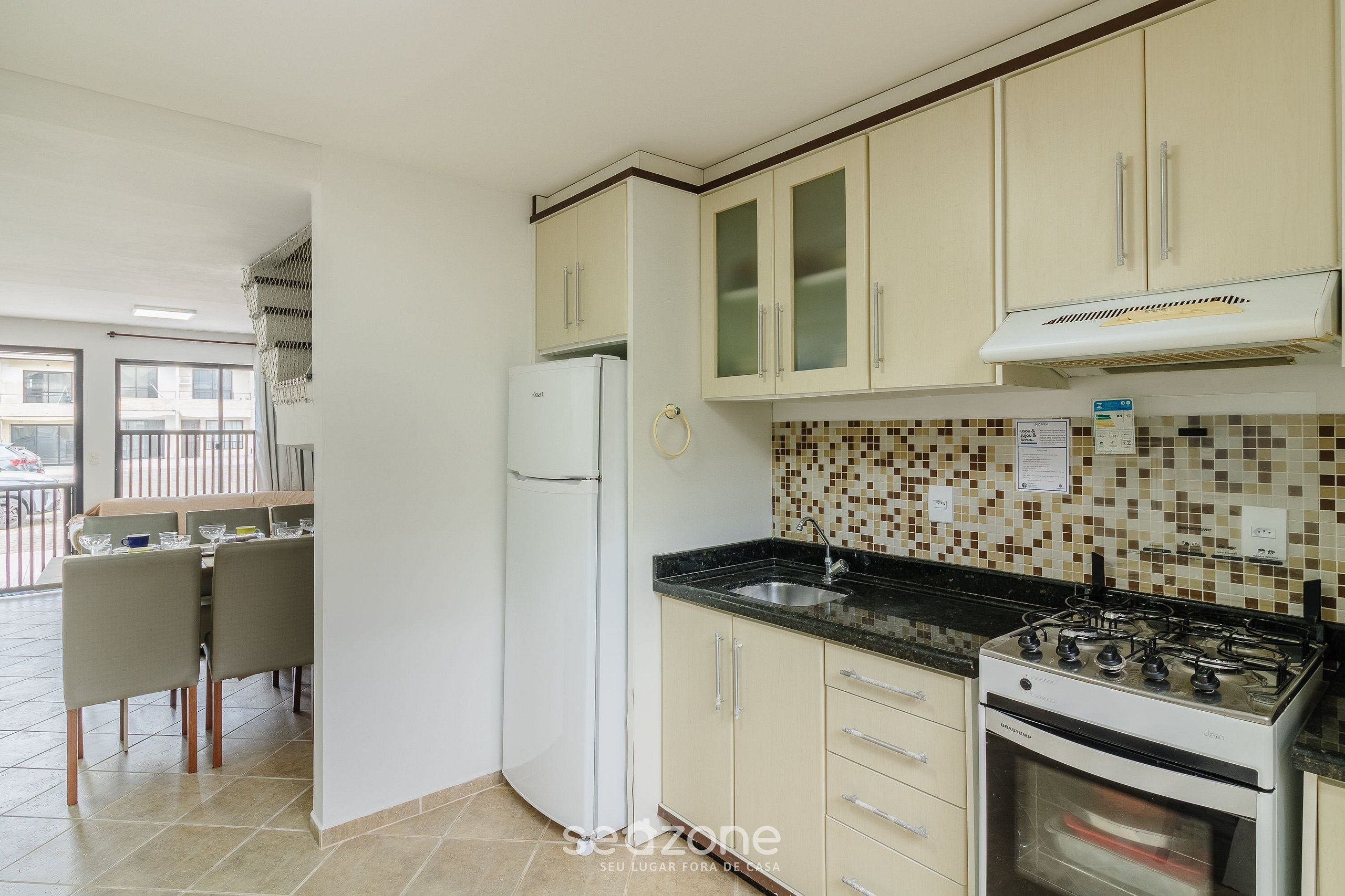 A kitchen with beige cabinets, a white refrigerator, a gas stove, and a tiled backsplash.