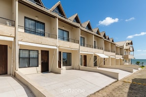 A multi-story hotel with balconies, large windows, and a paved courtyard.