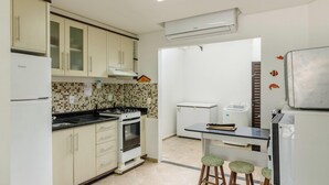 A compact kitchen with a stove, oven, and a small dining area with stools. - Houses in a Beachfront Condominium With a Swimming Pool in Itajuba - Mcss (Barra Velha)