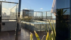 Une terrasse moderne sur le toit, dotée d’une piscine, de plantes en pot et offrant une vue sur la ville.