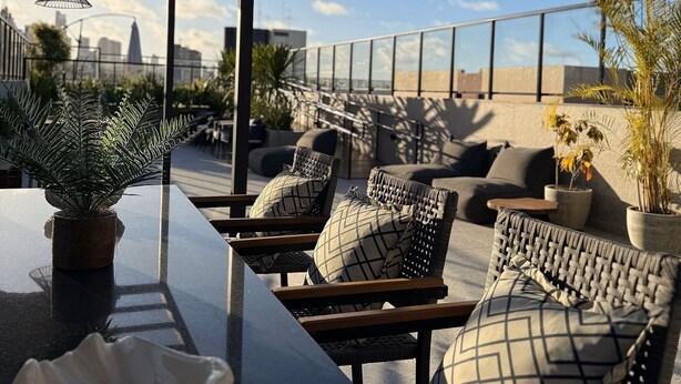Une terrasse sur le toit avec des espaces de détente en plein air, un bar et des plantes en pot.