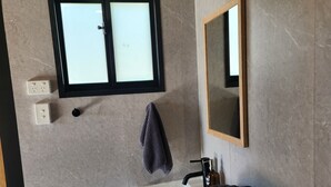 Ein Badezimmer mit Fenster, Waschbecken, Spiegel und Handtuchhalter.