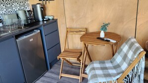 Eine kompakte Küche mit Mikrowelle, Kaffeemaschine und einer kleinen Essecke mit Holztisch und Stühlen.