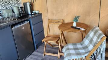 A compact kitchen with a microwave, coffee maker, and a small dining area with a wooden table and chairs.