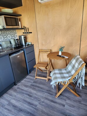 A compact kitchen with a microwave, coffee maker, and a small dining area with a wooden table and chairs. - Dam It Getaway Posh Pod
Beautiful tiny home- pet Friendly (Bowman Farm)