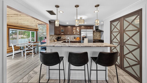 A modern kitchen with a large island, bar stools, and pendant lighting.