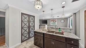 A modern kitchen with granite countertops, dark cabinetry, and pendant lighting.
