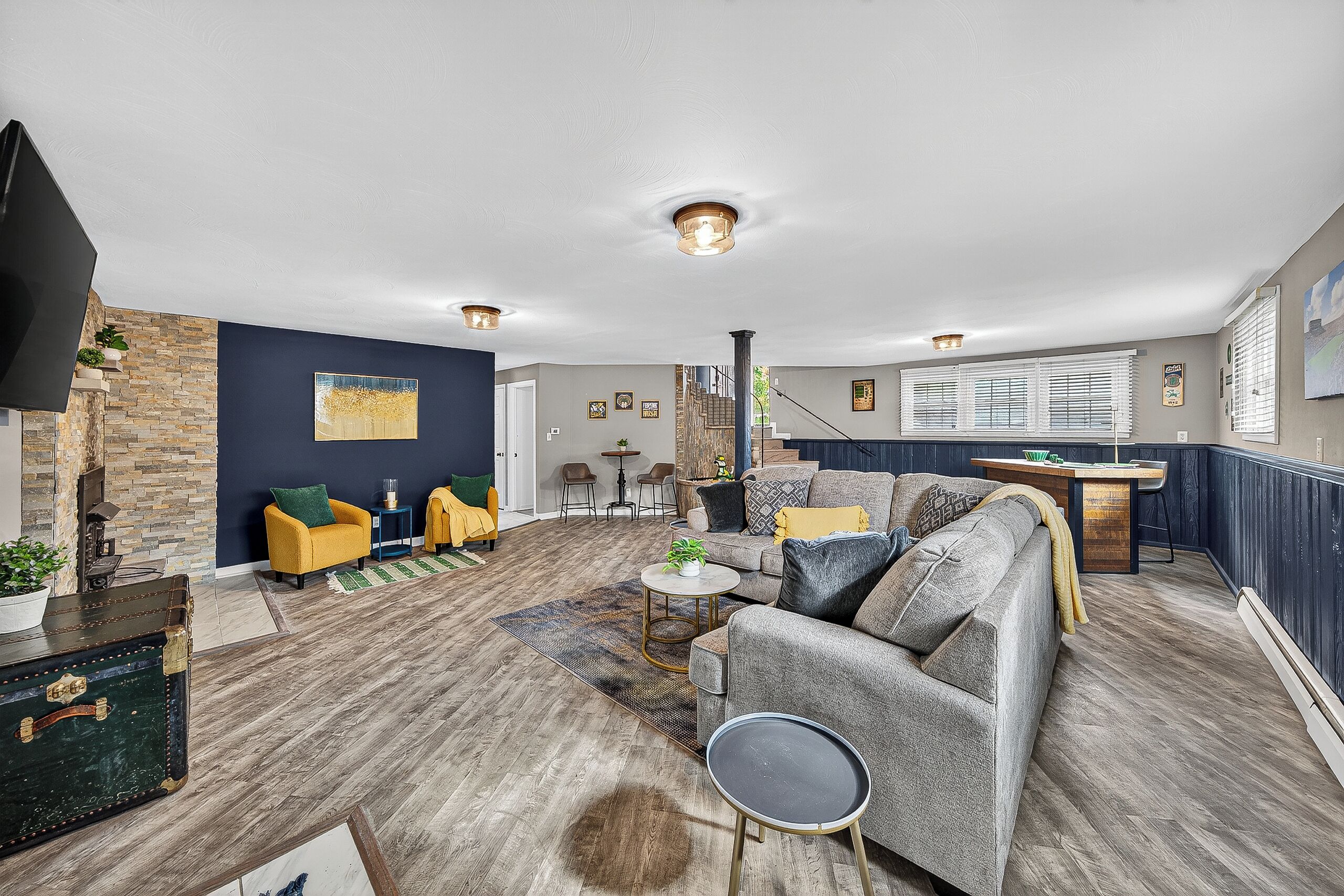 A spacious living area with a grey sofa, yellow armchairs, a coffee table, and a stone accent wall.