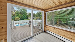 A wooden deck with a sliding glass door leading to an outdoor area with a pool and patio furniture.