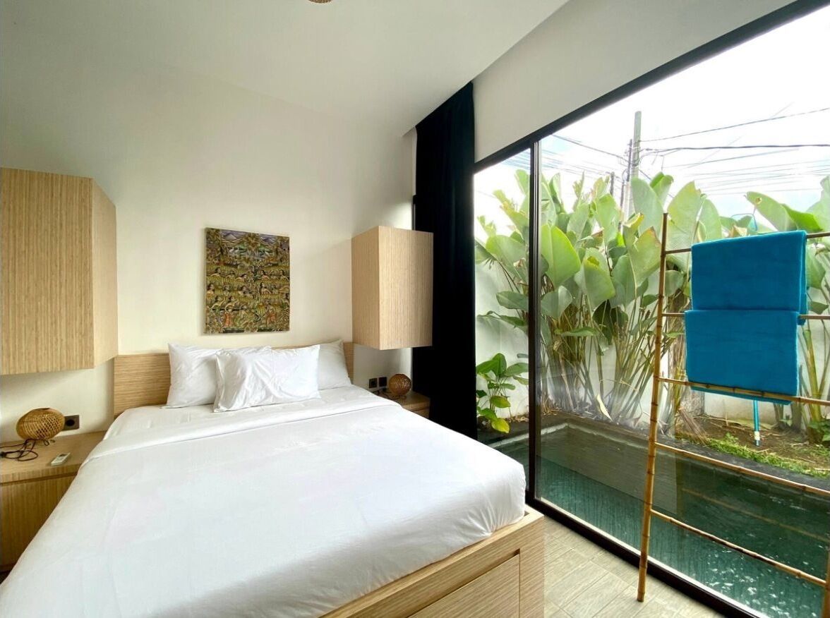 Ein modernes Hotelzimmer mit einem großen Bett, Blick auf einen Wasserspielplatz und ein Balkon mit Pflanzen.