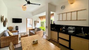 A modern kitchen with a wooden table, wicker furniture, and a black countertop. - Boutique Bohemian Villa in Canggu's Heart. (Kancil)