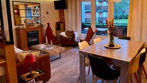 A cozy living room with a fireplace, a dining table, and a TV. - Christmas Apt | Parking + Balcony | Near Center (Morzine)