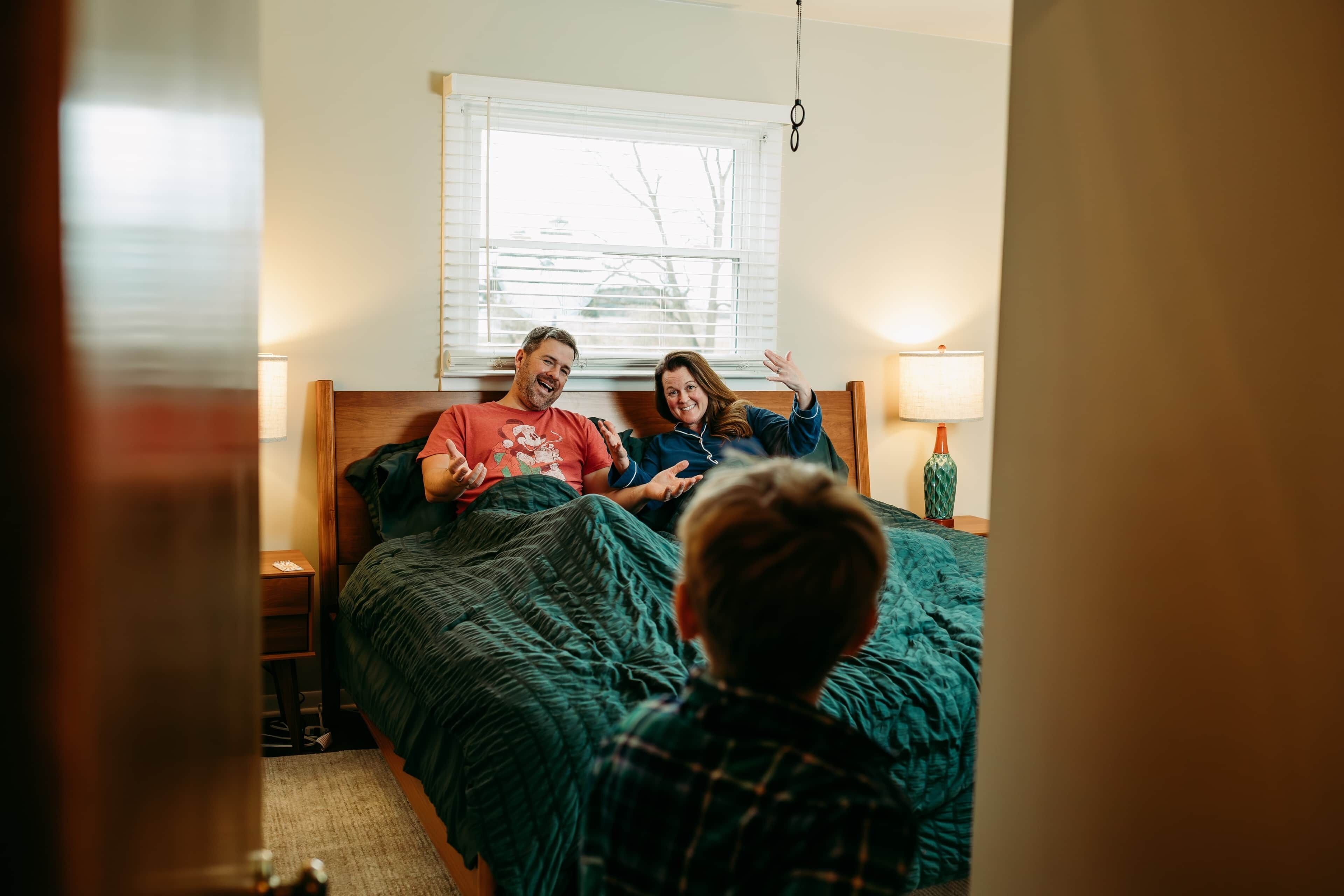 A bedroom with a bed, a window, and a nightstand with a lamp.