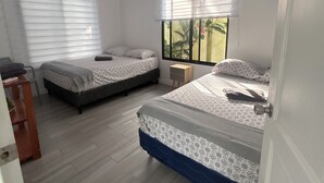 A bedroom with two beds, a small wooden nightstand, and a window with blinds. - Charming 1-bedroom villa in superb Bahia with AC (Bahia)