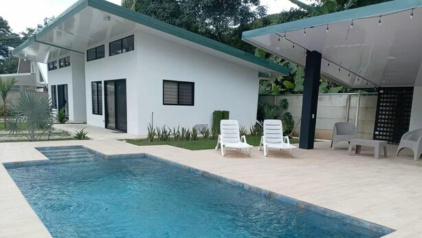 A modern house with a swimming pool, white exterior, and a covered patio area with lounge chairs. - Charming 1-bedroom villa in superb Bahia with AC (Bahia)