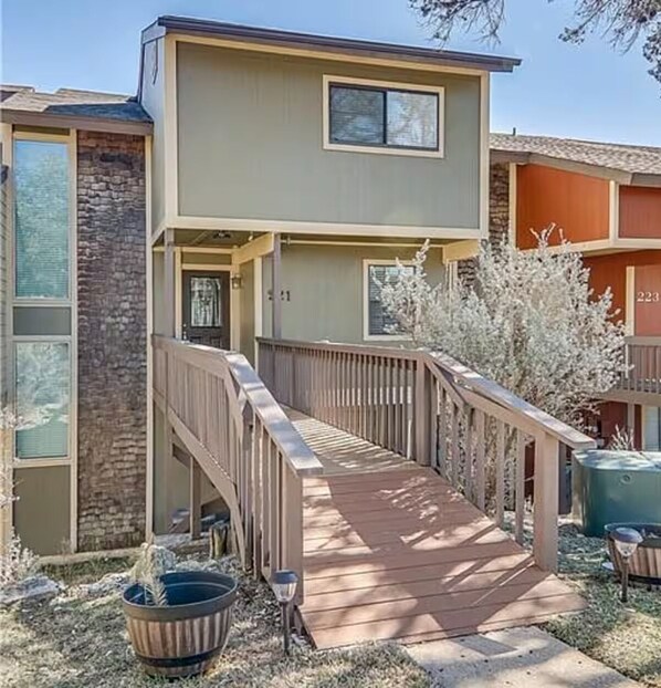 A two-story building with a wooden deck leading to the entrance. - Lake Views, Golf, Amenities, Austin Getaway (Leander)