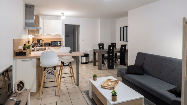 A modern apartment with a kitchen, dining area, and living room. It includes a sofa, a coffee table, and a TV. - Les reflets de loire (Chalonnes-sur-Loire)
