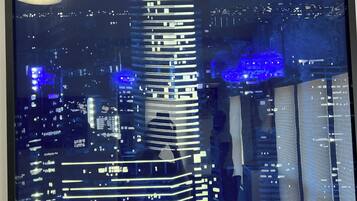 Een nachtelijke stadsgezicht met verlichte wolkenkrabbers, waaronder een opvallend gebouw met horizontale lijnen en een blauw verlichte top.