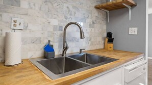 A kitchen with a double sink, marble backsplash, wooden countertop, and a knife block. - Scottsdale, Walk to Old Town + Pool/Hot Tub, 1BD:1BTH (Scottsdale)