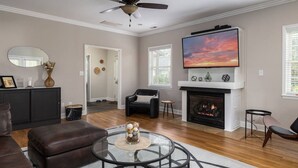A living room with a fireplace, a television, and a ceiling fan. - Greensboro`s Gem! Group Friendly, Central Location (Greensboro)