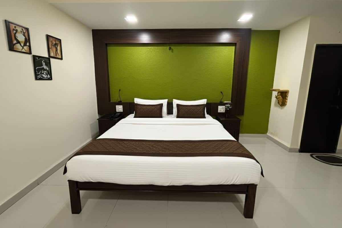 A hotel room with a large bed, green accent wall, and artwork on the wall.