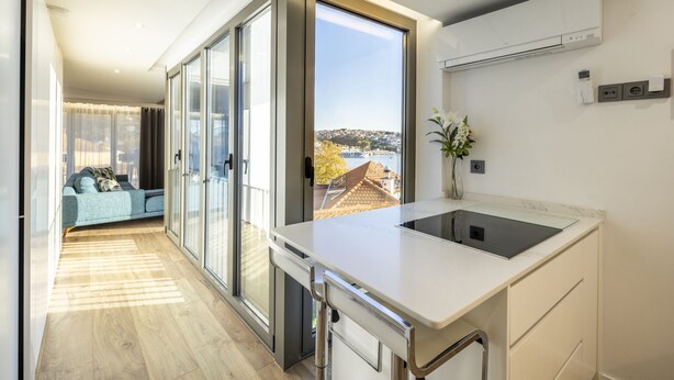 Eine moderne Küche mit einem großen Fenster, einem eingebauten Backofen und Blick auf die Stadt.