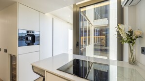 Eine moderne Küche mit eingebautem Backofen, einer Glasrückwand und Blick auf die Innentreppe.